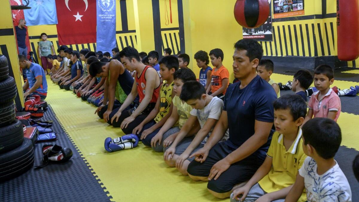 In this photograph taken on August 29, 2019, trainers and children from Muslim Uighur minority pray as they attend a Muay Thai training session in a boxing academy in Istanbul. BULENT KILIC / AFP
