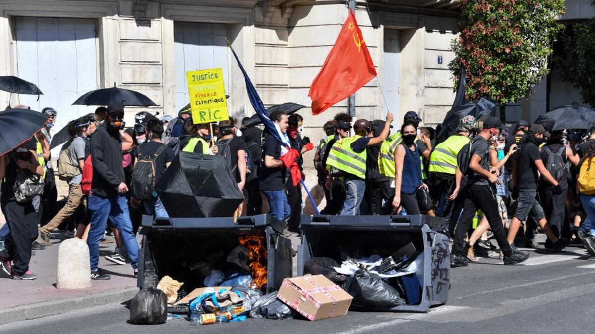 Protesters walk past burning trash bins during an anti-government demonstration called by the "Yellow Vests" (Gilets Jaunes) movement on September 7, 2019 in Montpellier, southern France. Pascal GUYOT / AFP