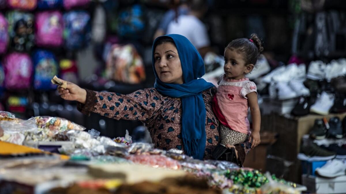 A woman pays a merchant at a market in the Kurdish-majority city of Qamishli in northeast Syria.  Delil SOULEIMAN / AFP