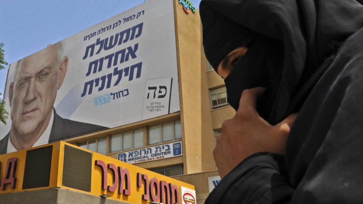 A Bedouin woman walks below an electoral banner for the Blue and White (Kahol Lavan) electoral alliance bearing the portrait of retired general Benny Gantz with a caption in Hebrew reading "only with the Blue and White we will create a united secular government" in the southern Israeli city of Beersheva on September 15, 2019. HAZEM BADER / AFP