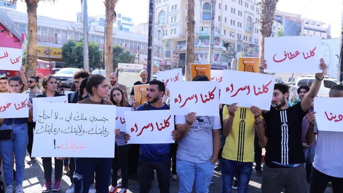Arabic slogans on placards call for an end to violence against women and introducing a law for family protection against domestic violence."  (Twitter)