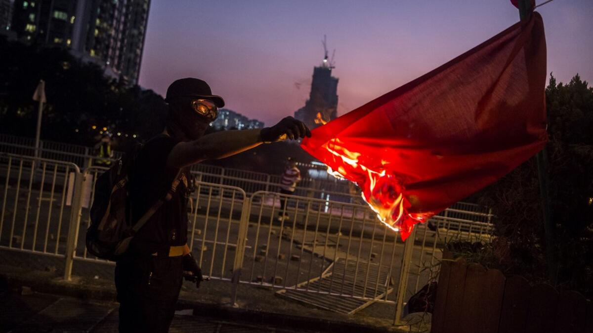 A protester sets fire to the Chinese national flag in the Sha Tin district of Hong Kong on October 1, 2019, as violent demonstrations take place in the streets of the city on the National Day holiday to mark the 70th anniversary of communist China's founding. ISAAC LAWRENCE / AFP