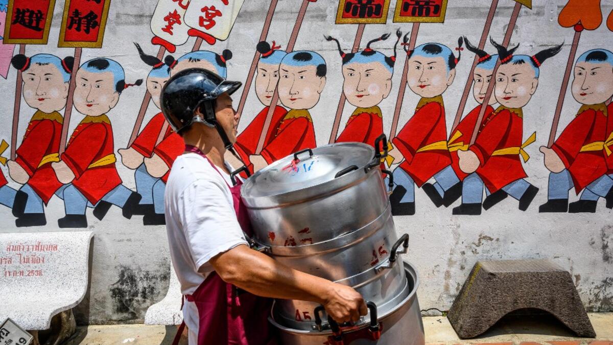 A volunteer carries empty pots at a Chinese shrine during the annual Vegetarian Festival in Phuket on October 5, 2019. Mladen ANTONOV / AFP