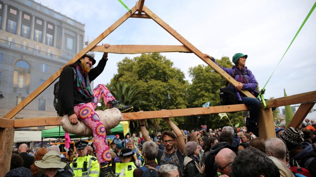 Climate change activists from the group Extinction Rebellion sit atop a temporary wooden structure as they demonstrate on Lambeth Bridge in central London, on October 7, 2019. Extinction Rebellion has scheduled non-violent protests chiefly in Europe, North America and Australia over the next fortnight. ISABEL INFANTES / AFP