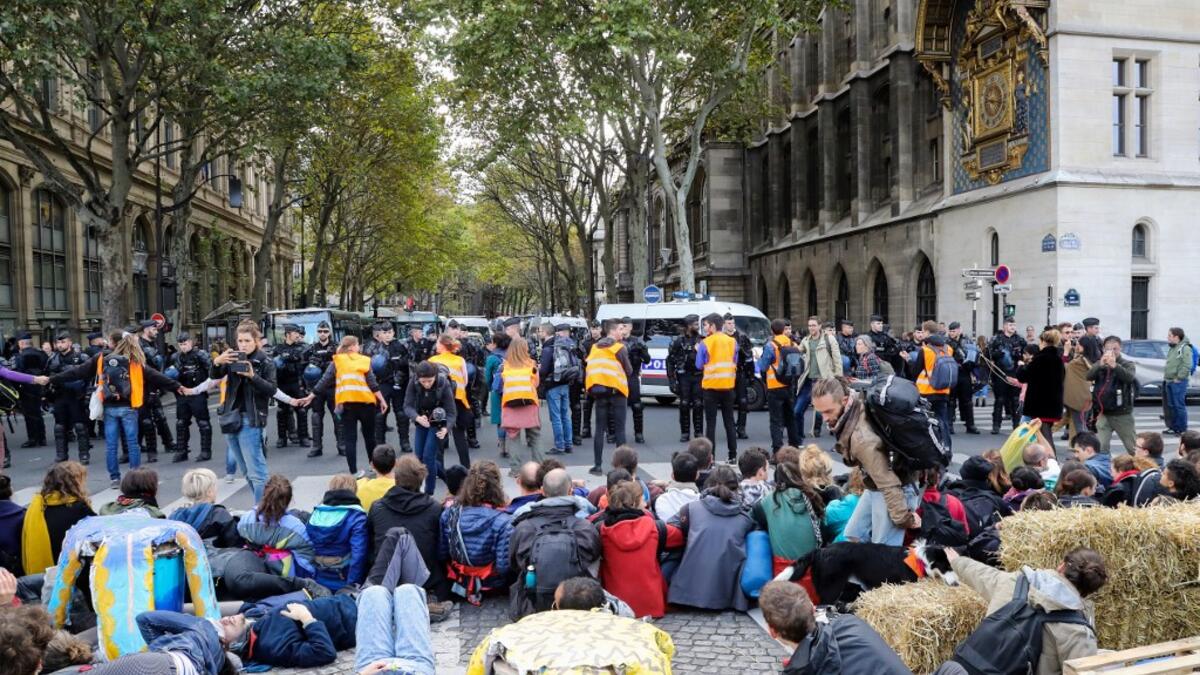 French Gendarmes stand ready as protesters sit on the ground to block the Pont au Change bridge during a demonstration called by climate change activist group Extinction Rebellion, on October 7, 2019 in front of the Conciergerie in Paris. AFP