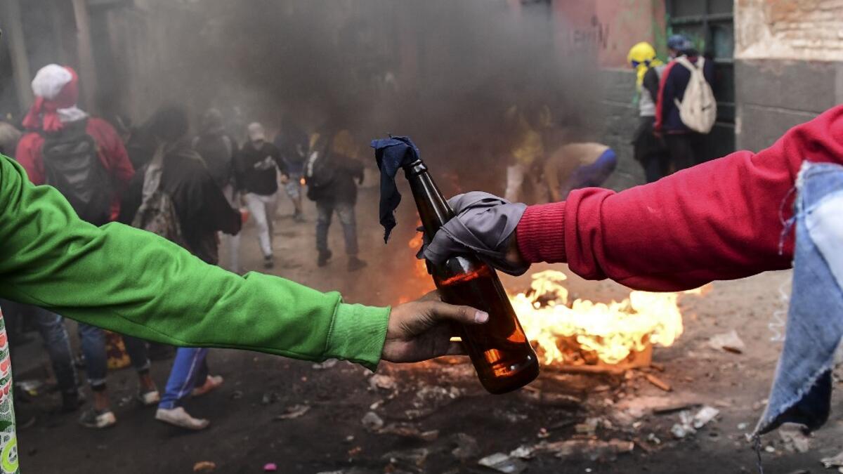 Demonstrators pass on a Molotov cocktail during clashes with riot police in Quito on October 9, 2019 on the second day of violent protests over a fuel price hike ordered by the government to secure an IMF loan. Martin BERNETTI / AFP