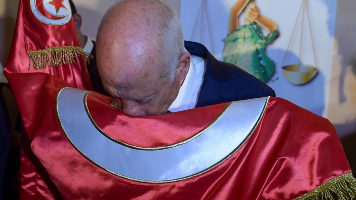 Conservative academic Kais Saied kisses the Tunisian flag as he celebrates his victory in the Tunisian presidential election in the capital Tunis on October 13, 2019. Saied won a landslide victory in Tunisia's presidential runoff, sweeping aside his rival, media magnate Nabil Karoui, state television Wataniya said. It said he scooped almost 77 percent of the vote, compared to 23 percent for Karoui. Fethi Belaid / AFP