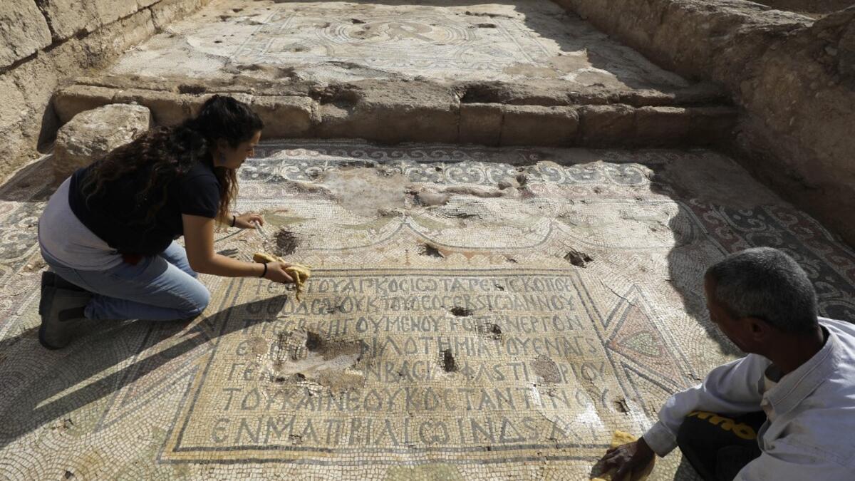 Timnah Goloubin (L), an archaeologist with the Israel Antiquities Authority, shows on October 23, 2019 a mosaic inscription in ancient Greek mentioning a donation received from Emperor Tiberius II, in the Israeli town of Bet Shemesh. The magnificent 1500-year-old church, decorated with spectacular mosaic floors and Greek inscriptions, was discovered during a three-year excavation near a residential area. MENAHEM KAHANA / afp