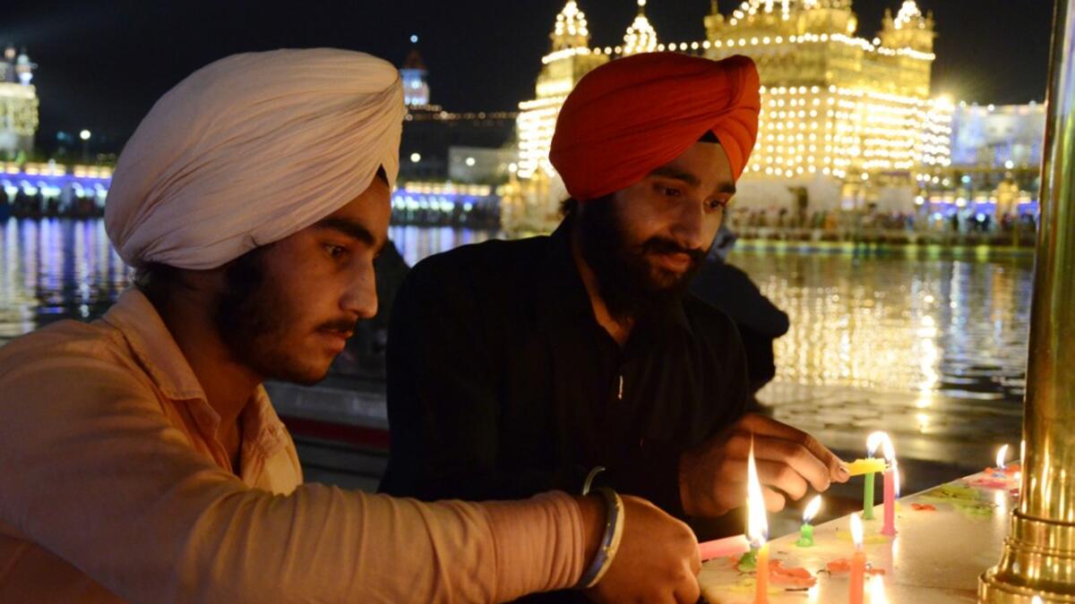 Indian Sikh devotees light candles as they pay their respects on the eve of "Bandi Chhor Divas" or "Diwali" at the illuminated Golden Temple, in Amritsar on October 26, 2019. Sikhs celebrate 'Bandi Chhor Divas', also on the same day as the Hindu festival of Diwali, to mark the historic return of the sixth Guru, Guru Hargobind NARINDER NANU / AFP