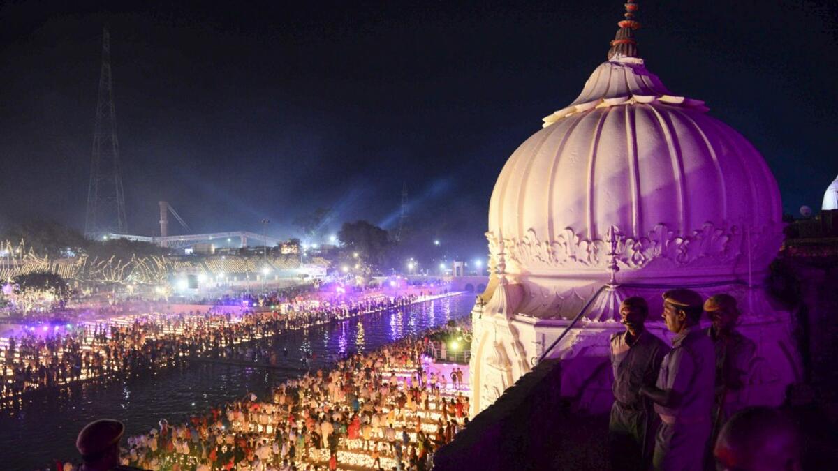 Indian security personnel keep watch as Hindu devotees light earthen lamps on the banks of the River Sarayu on the eve of "Diwali" festival during an event organised by the Uttar Pradesh government, in Ayodhya on October 26, 2019. "Diwali", the Festival of Lights, marks victory over evil and commemorates the time when Hindu god Lord Rama achieved victory over Ravana and returned to his kingdom Ayodhya. SANJAY KANOJIA / AFP