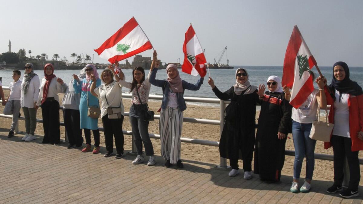 Lebanese protesters hold hands to form a human chain along the coast from north to south as a symbol of unity, during ongoing anti-government demonstrations in the southern Lebanese port city of Sidon on October 27, 2019. Mahmoud ZAYYAT / AFP