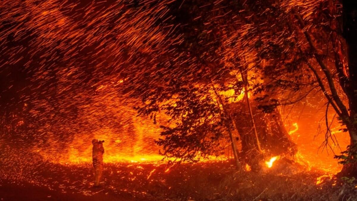 A photographer takes photos amid a shower of embers as wind and flames rip through the area during a wildfire near Geyserville, Calif. (Josh Edelson/AFP via Getty Images)