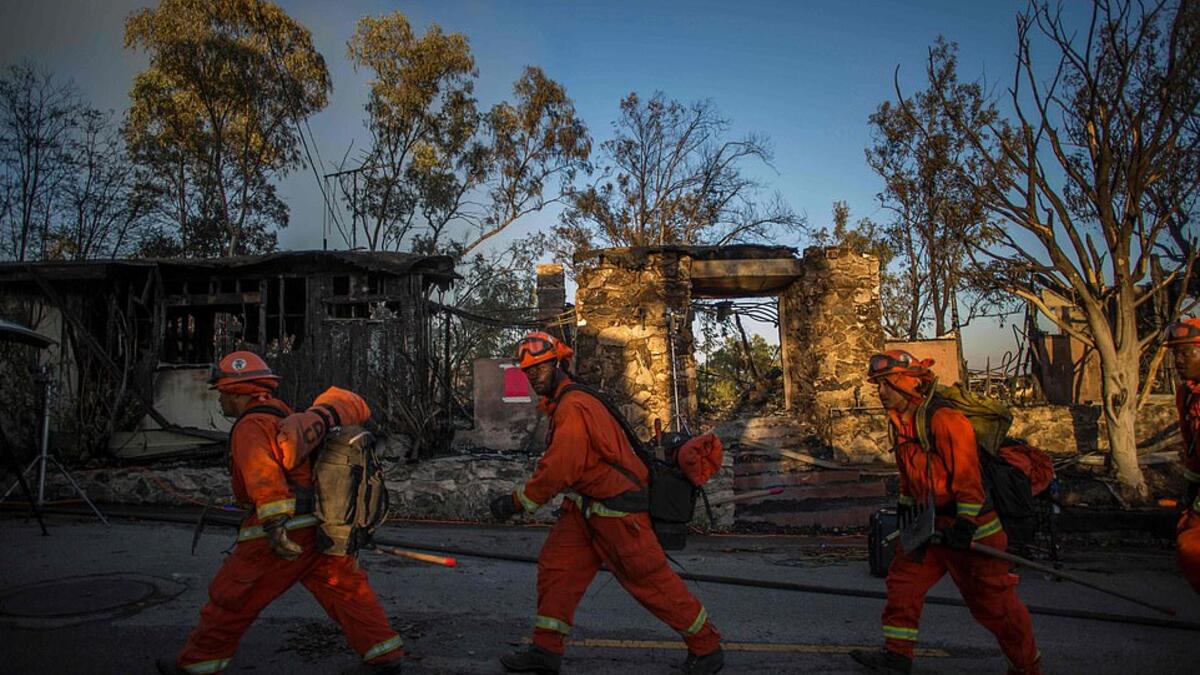 Into the inferno: Inmate firefighters walk past a burned home as they prepare to battle the wind-driven blaze in Brentwood, California which has destroyed several homes and forced schools to shut. (AFP)