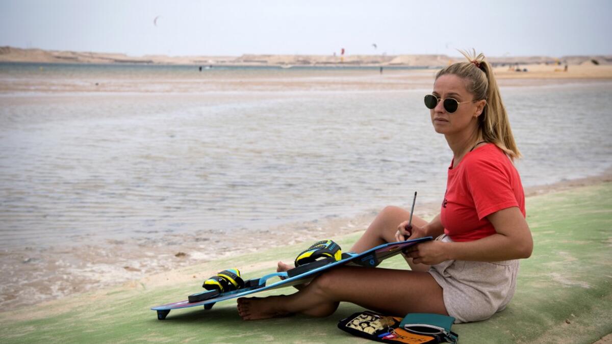 A picture taken on October 10, 2019, shows a kitesurfer fixing her board at Dakhla beach in Morocco-administered Western Sahara. In the heart of disputed Western Sahara, a former garrison town has become an unlikely tourist magnet after kitesurfers discovered the windswept desert coast on the Atlantic is perfect for their sport. FADEL SENNA / AFP