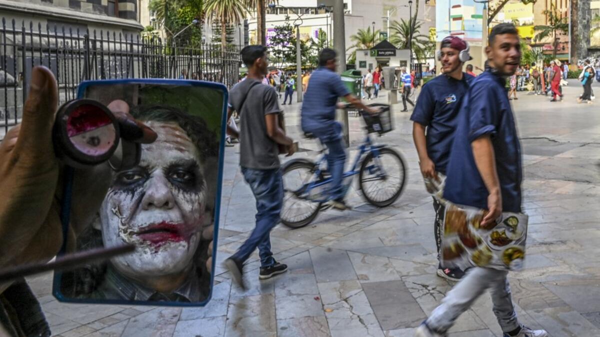 Venezuelan migrant Johnny Tales, who makes a living imitating the comicbook and film character "The Joker", applies make up as he prepares to perform in downtown Medellin, on October 28, 2019. JOAQUIN SARMIENTO / AFP