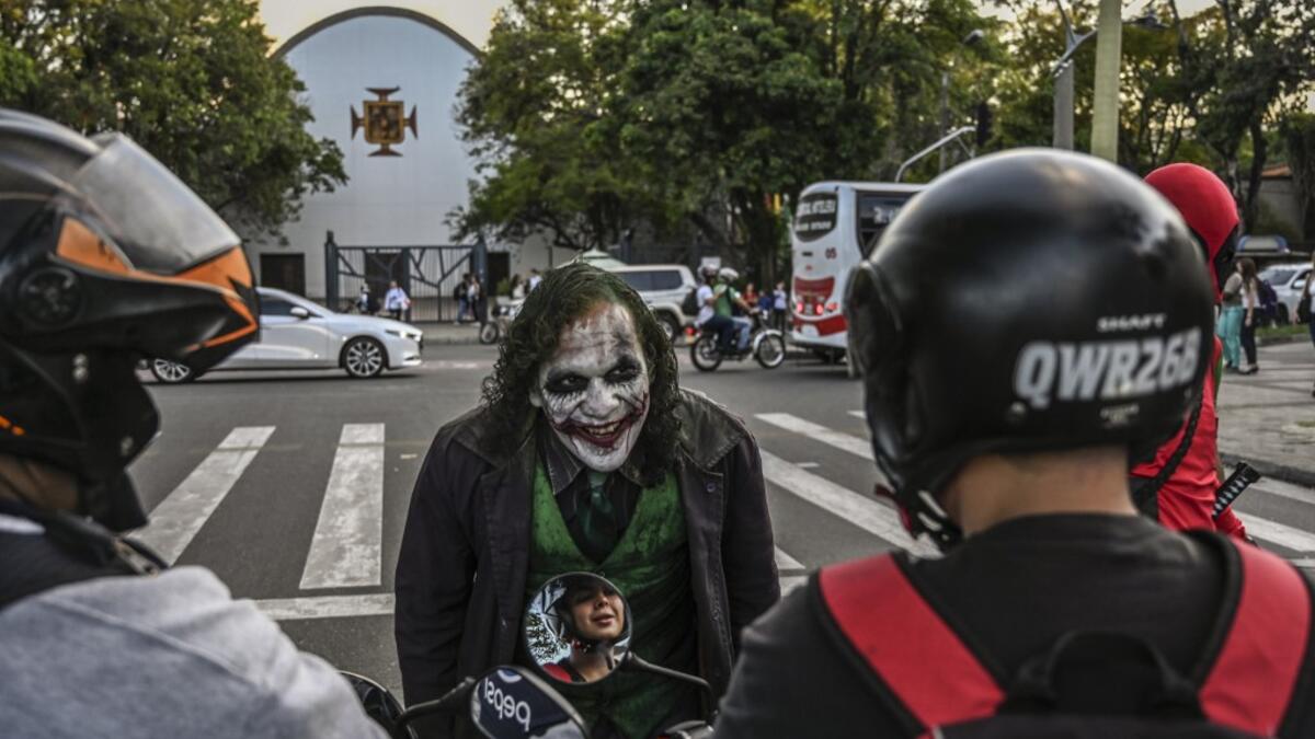 Venezuelan migrant Johnny Tales, who makes a living imitating the comicbook and film character "The Joker", performs at a traffic light in Medellin, on October 29, 2019. JOAQUIN SARMIENTO / AFP