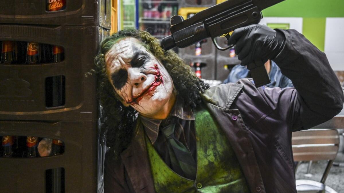Venezuelan migrant Johnny Tales (R), who makes a living imitating the comicbook and film character "The Joker", poses at a convenience store in Medellin, on October 29, 2019. JOAQUIN SARMIENTO / AFP