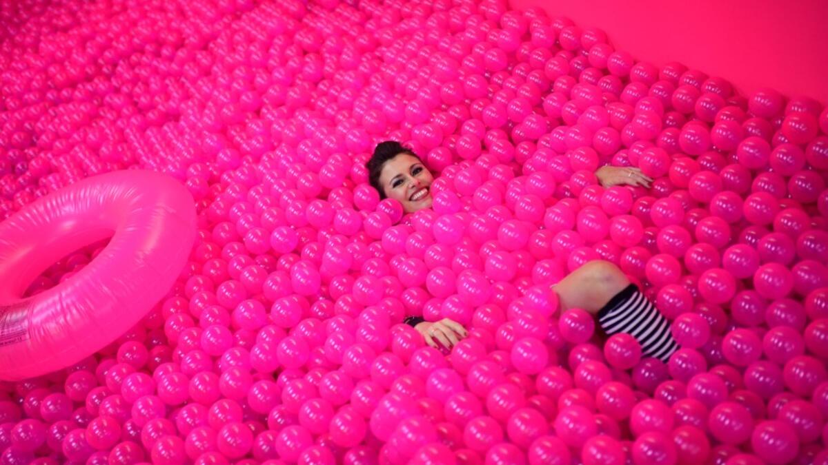 A woman smiles, while lying in a ball bath, at the "Supercandy Pop-Up Museum Vol. 2" in Cologne, western Germany on November 1, 2019. It is an interactive museum and offers a photo backdrop for social media at 25 stations. INA FASSBENDER / AFP