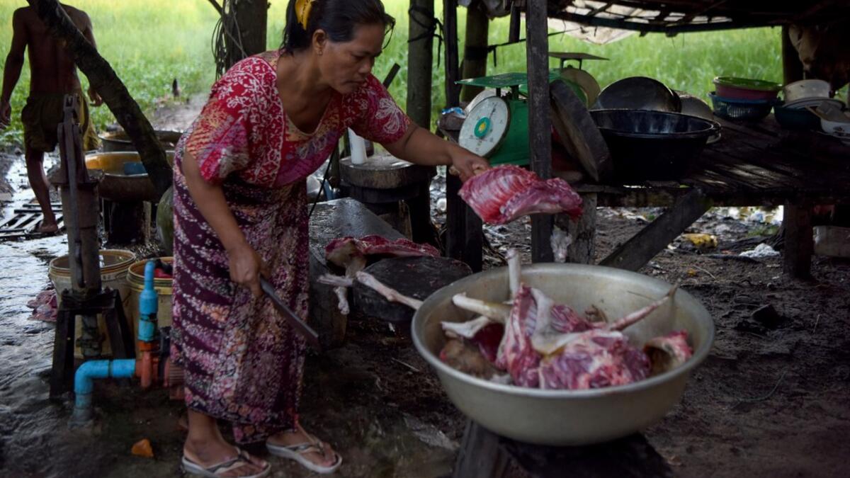 This photo taken on October 25, 2019 shows a woman preparing dog meat for customers at a slaughterhouse in Siem Reap province. Cambodian dog meat traders drown, strangle and stab thousands of canines a day in a shadowy but sprawling business that traumatises workers and exposes them to deadly health risks like rabies. TANG CHHIN Sothy / AFP