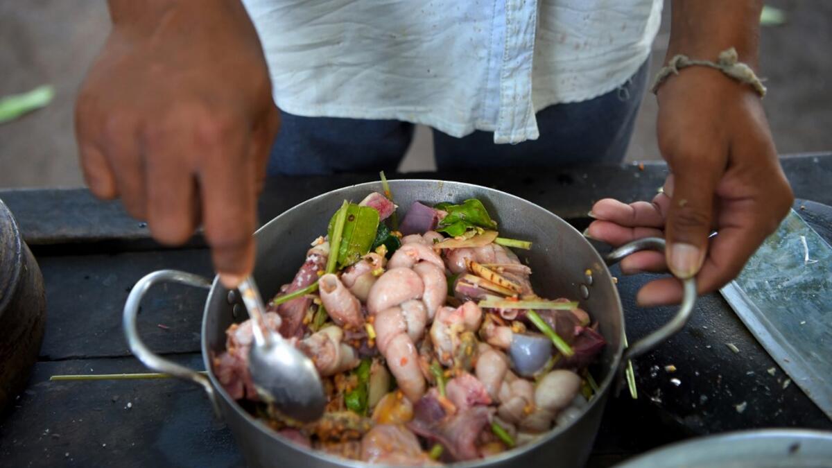 This photo taken on October 25, 2019 shows a man preparing to cook dog meat at a slaughterhouse in Siem Reap province. Cambodian dog meat traders drown, strangle and stab thousands of canines a day in a shadowy but sprawling business that traumatises workers and exposes them to deadly health risks like rabies. TANG CHHIN Sothy / AFP