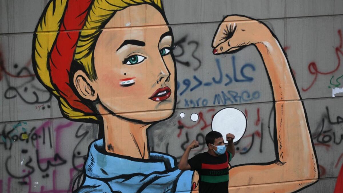 An Iraqi protester poses in front of a mural at Baghdad's Tahrir square during ongoing anti-government demonstrations on November 2, 2019. Iraqi security forces clashed with anti-government protesters in the early hours of Saturday near the capital's Tahrir Square, leaving one demonstrator dead and dozens more wounded, medical sources said. AHMAD AL-RUBAYE / AFP