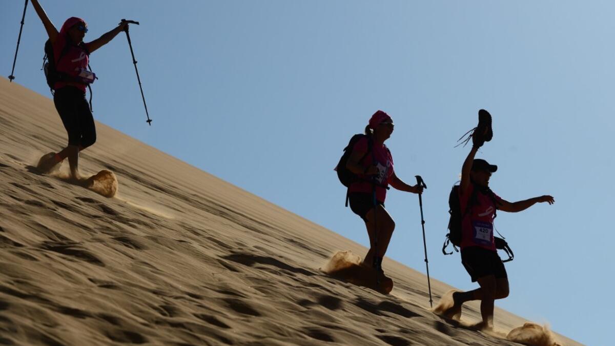 Women run down a sand dune as they take part in the desert trek "Rose Trip Maroc", on November 4, 2019 in the erg Chebbi near Merzouga. The Rose Trip Maroc is a female-oriented trek where teams of three must travel through the southern Moroccan Sahara desert with a compass, a map and a topographical reporter. JEAN-PHILIPPE KSIAZEK / AFP