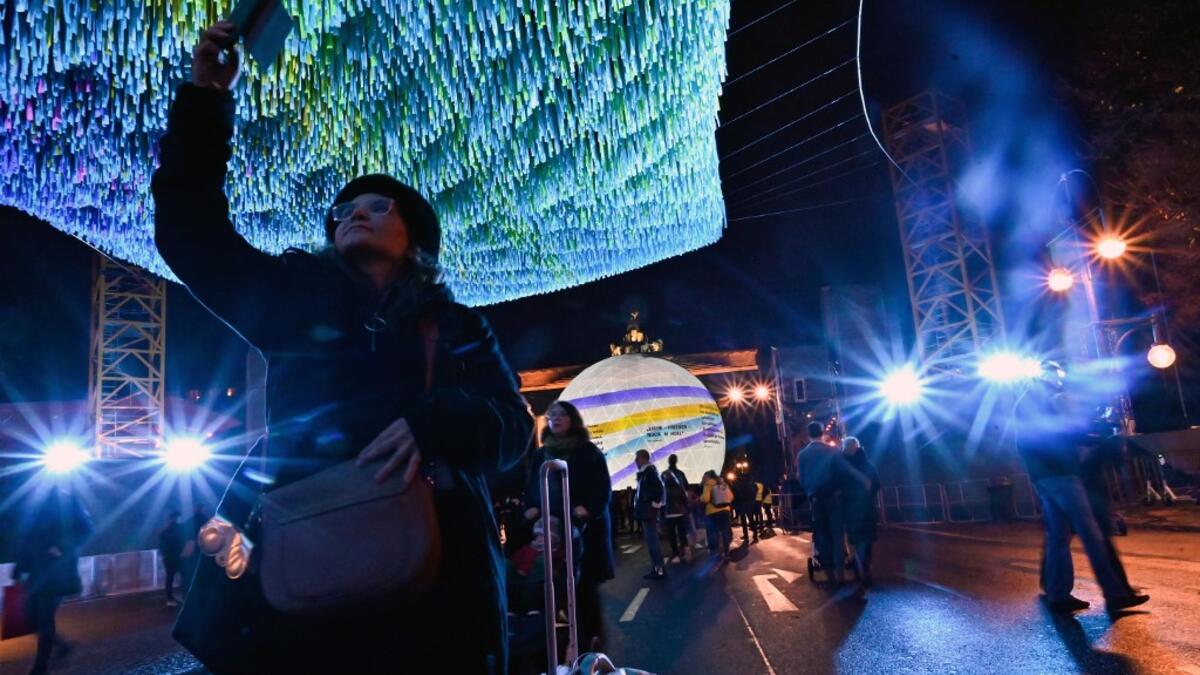 Visitors walk under installation "Visions in Motion" by artist Patrick Shearn and his studio Poetic Kinetics in front of Berlin's landmark the Brandenburg Gate on November 4, 2019 in Berlin. As Germany and it's capital Berlin will celebrate the 30th anniversary of the Fall of the Wall, the skynet made of 30,000 ribbons that bear aloft the wishes, hopes, and memories of 30,000 people today will be on display from November 4 to 10, 2019. Tobias SCHWARZ / AFP