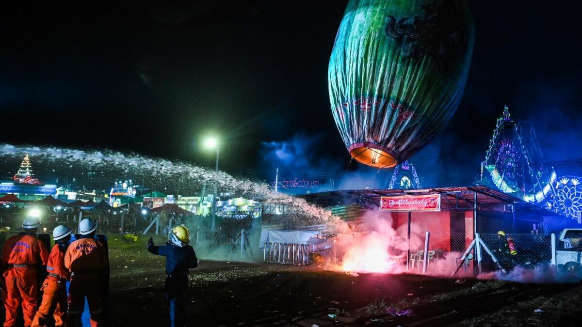 This picture taken on November 4, 2019 shows firefighters at work after a fireworks-laden hot-air balloon ignited before the balloon was at a sufficient height during during the Tazaungdaing Lighting Festival at Taunggyi in Myanmar's northeastern Shan State. Brightly coloured balloons with hundreds of homemade fireworks woven into their frames are sent soaring into the night sky, showering down cascades of sparks onto adoring crowds in the annual Taunggyi fire balloon festival. Ye Aung THU / AFP