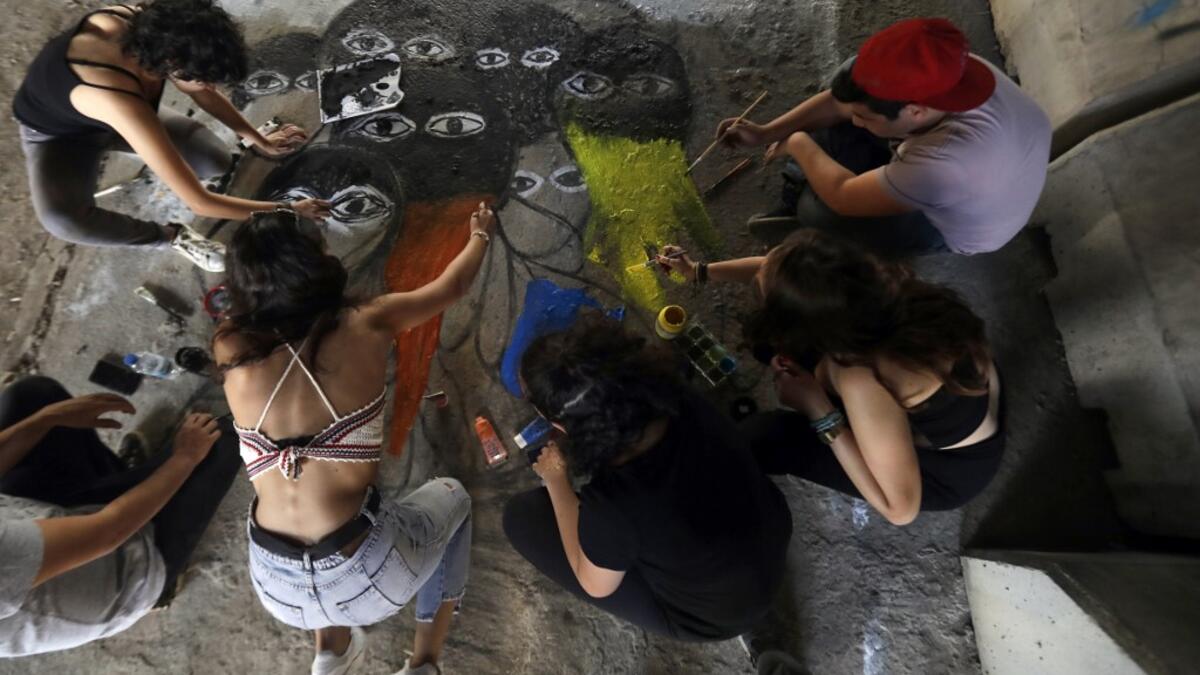 Lebanese anti-government protesters paint a graffiti on the ground in central Beirut on November 5, 2019. Since October 17, the chanting of tens of thousands of Lebanese denouncing the political elite have shaken the normally staid district around two Beirut squares, Martyrs' and Riad Al Solh. JOSEPH EID / AFP