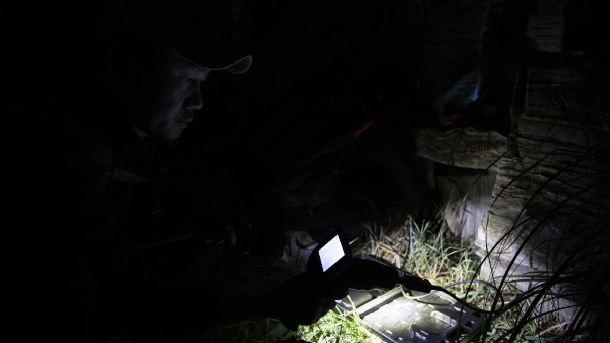 This photo taken on October 23, 2019 shows pet detective Sun Jinrong using a night vision camera as he searches for a missing cat in a residential compound in Beijing. Private sleuth Sun Jinrong brings heat detectors, tiny surveillance cameras, and a blowdart loaded with a tranquiliser to his search for one desperate client's missing loved one: A cat named Duoduo.  NOEL CELIS / AFP