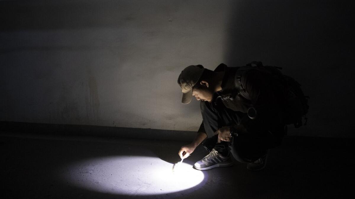 This photo taken on October 23, 2019 shows pet detective Sun Jinrong checking for feline droppings as he searches for a missing cat in a residential compound in Beijing. Private sleuth Sun Jinrong brings heat detectors, tiny surveillance cameras, and a blowdart loaded with a tranquiliser to his search for one desperate client's missing loved one: A cat named Duoduo.  NOEL CELIS / AFP