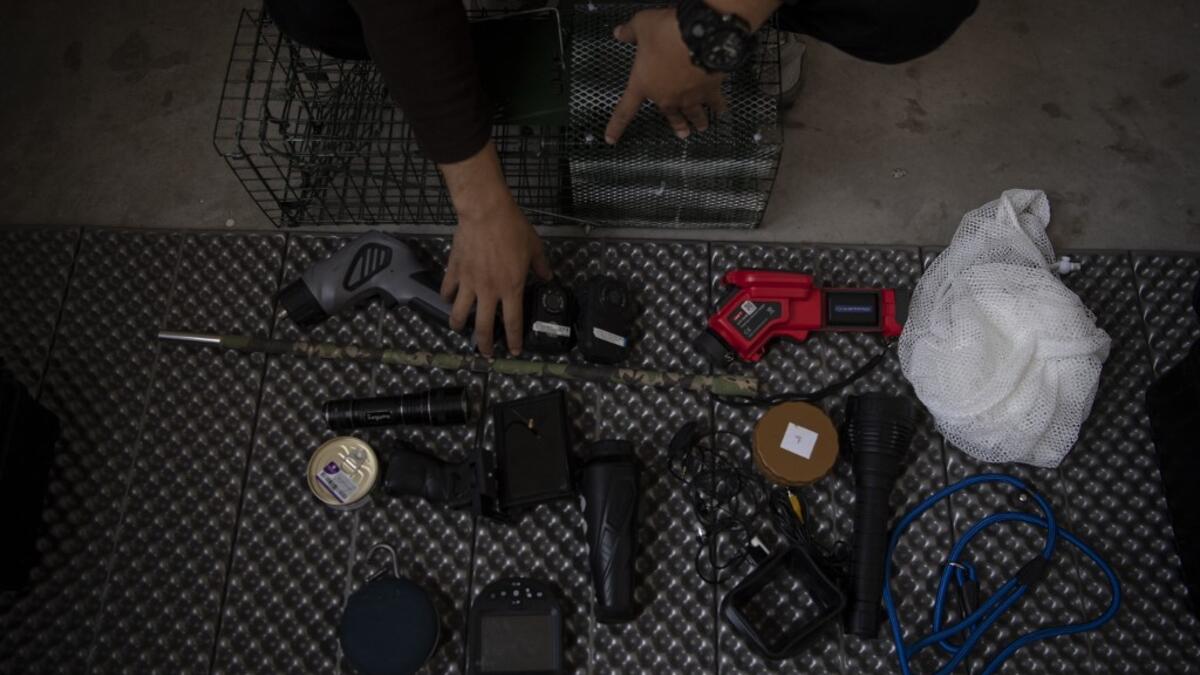 This photo taken on October 23, 2019 shows pet detective Sun Jinrong sitting next to his equipment as he prepares to search for a missing cat in a residential compound in Beijing. Private sleuth Sun Jinrong brings heat detectors, tiny surveillance cameras, and a blowdart loaded with a tranquiliser to his search for one desperate client's missing loved one: A cat named Duoduo.  NOEL CELIS / AFP