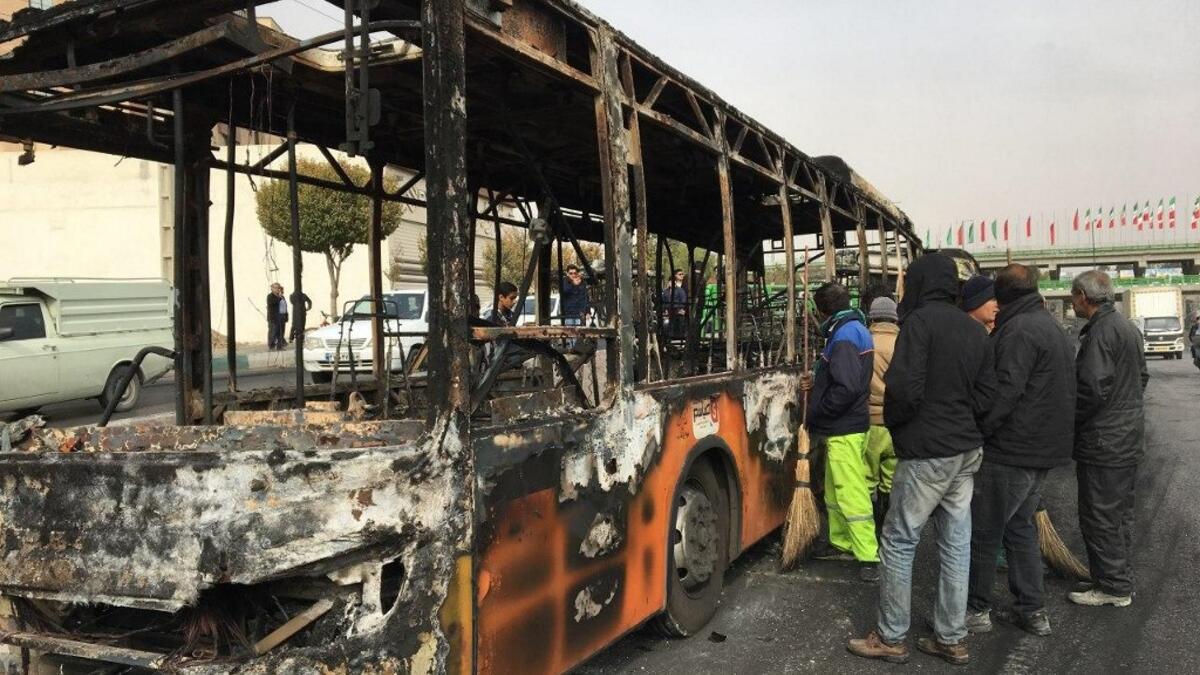 Iranians inspect the wreckage of a bus that was set ablaze by protesters during a demonstration against a rise in gasoline prices in the central city of Isfahan on November 17, 2019. AFP