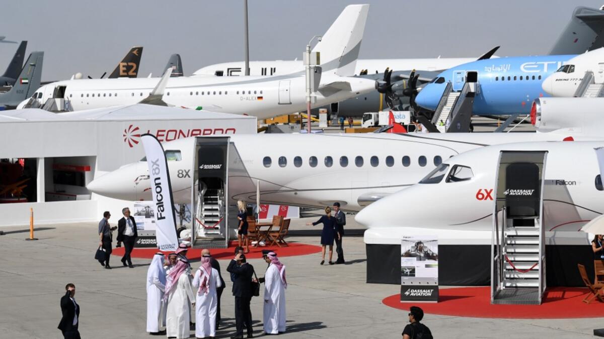 This picture taken on November 18, 2019 shows a general view of visitors walking past aircraft on display during the 2019 Dubai Airshow. KARIM SAHIB / AFP