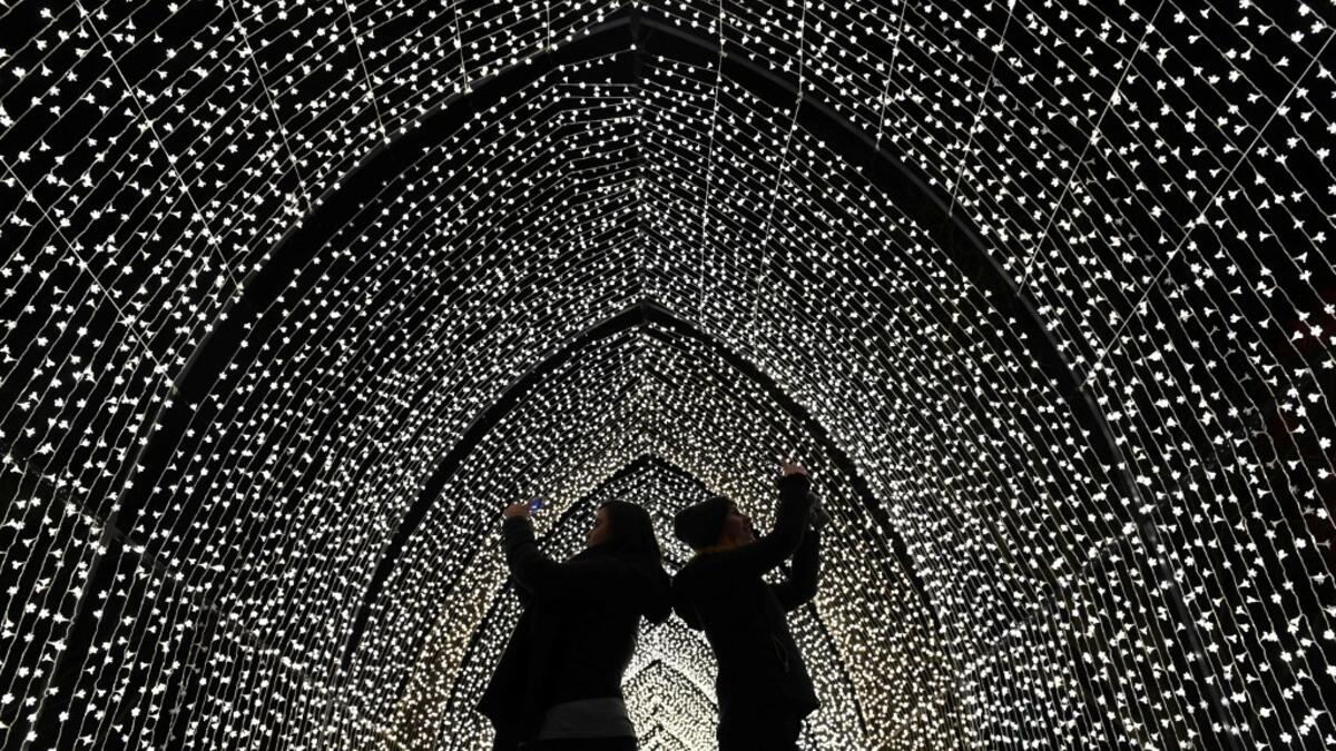 Visitors walk through the 'By Frost' tunnel of lights during a photocall at Kew Gardens in south west London, on November 19, 2019, during an event to promote the launch of the "Christmas at Kew" event. The Christmas at Kew trail is illuminated with numerous light-art installations especially commissioned. Daniel LEAL-OLIVAS / AFP