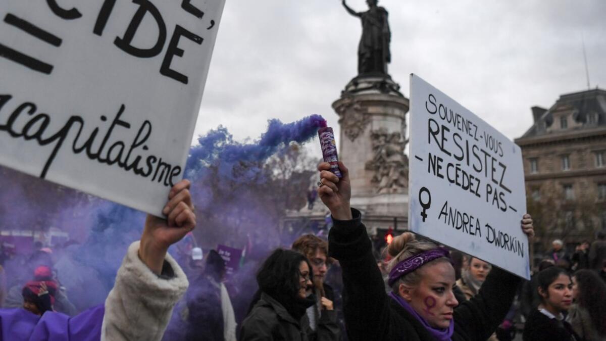 A woman holds a flare and a placard reading "Remember, resist, do not give in" during a protest to condemn violence against women, on November 23, 2019, in Paris. Alain JOCARD / AFP
