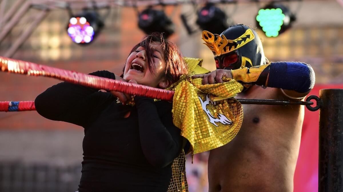 Bolivian wrestler Blanca Perez (L), aka "Katy The Beautiful", a member of the Fighting Cholitas, fights with a male wrestler at Sharks of the Ring wrestling club in El Alto, Bolivia, on November 24, 2019. After a fortnight hiatus due to anti-government protests and blockades, the Fighting Cholitas are back in the ring. The unrest was triggered by the disputed October 20 election, which Evo Morales claimed to have won and opposition groups said was rigged. Ronaldo SCHEMIDT / AFP