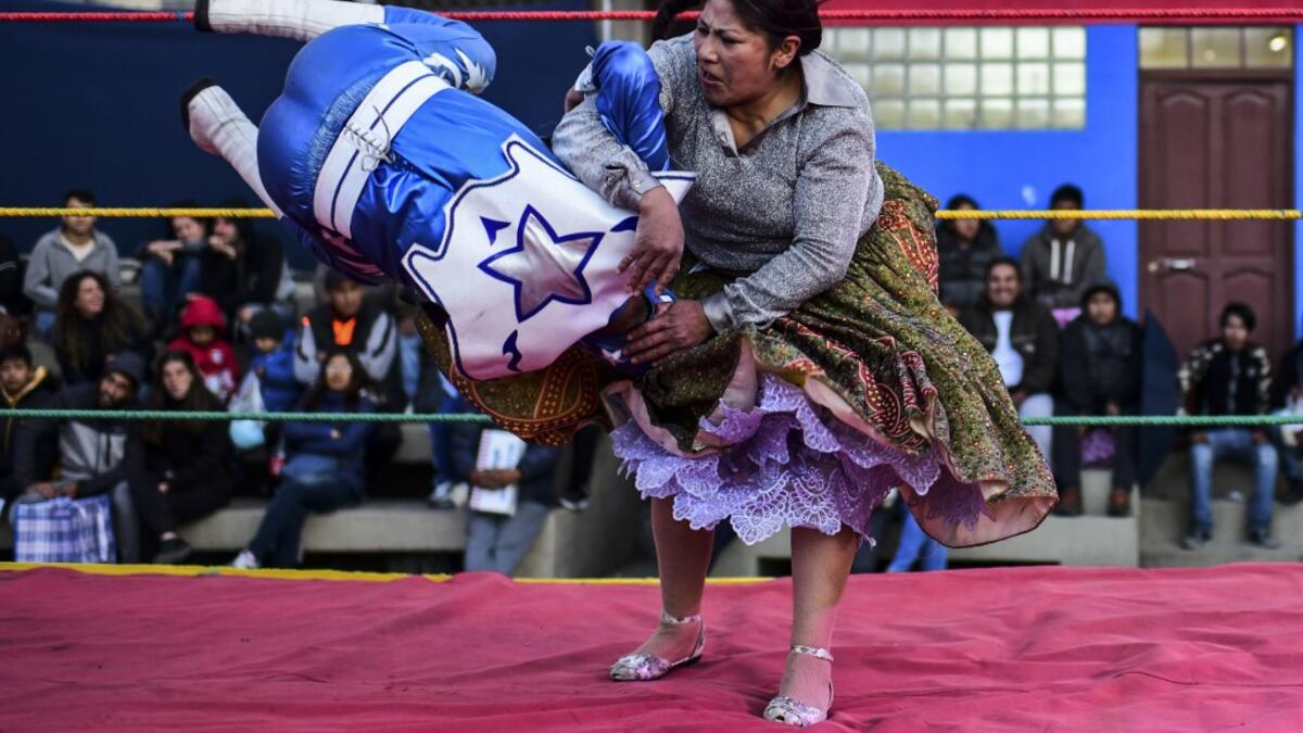 Bolivian wrestler Ana Luisa Yujra (R), aka "Jhenifer Two Faces", a member of the Fighting Cholitas, fights with a male wrestler at Sharks of the Ring wrestling club in El Alto, Bolivia, on November 24, 2019. After a fortnight hiatus due to anti-government protests and blockades, the Fighting Cholitas are back in the ring. The unrest was triggered by the disputed October 20 election, which Evo Morales claimed to have won and opposition groups said was rigged. Ronaldo SCHEMIDT / AFP