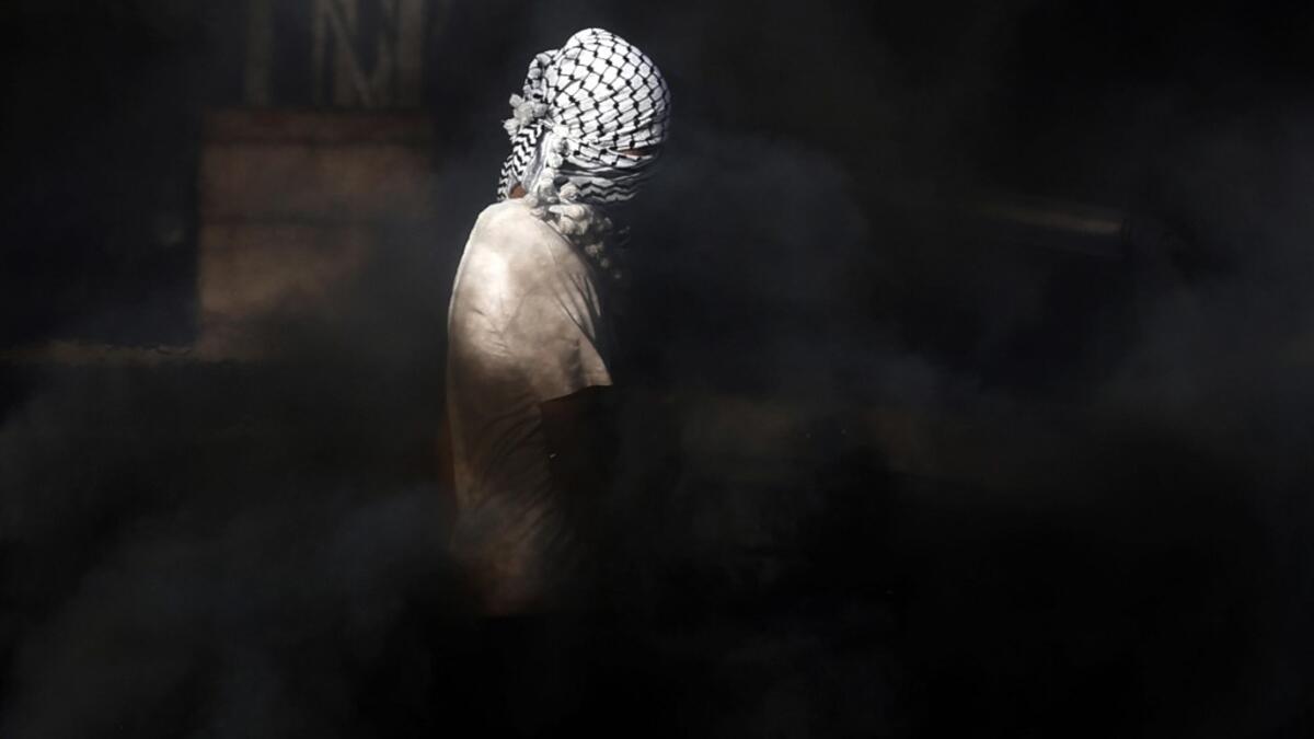 A masked Palestinian youth stands amidst smoke during clashes with Israeli security forces on November 26, 2019 near the West Bank city of Nablus as Palestinians stage a "day of rage" against a recent US decision to no longer consider settlements in the West Bank illegal. The US broke with decades of international consensus on November 18 as its secretary of state announced the country would no longer consider Israeli settlements in the occupied Palestinian territories illegal. Israel, led by its prime mini
