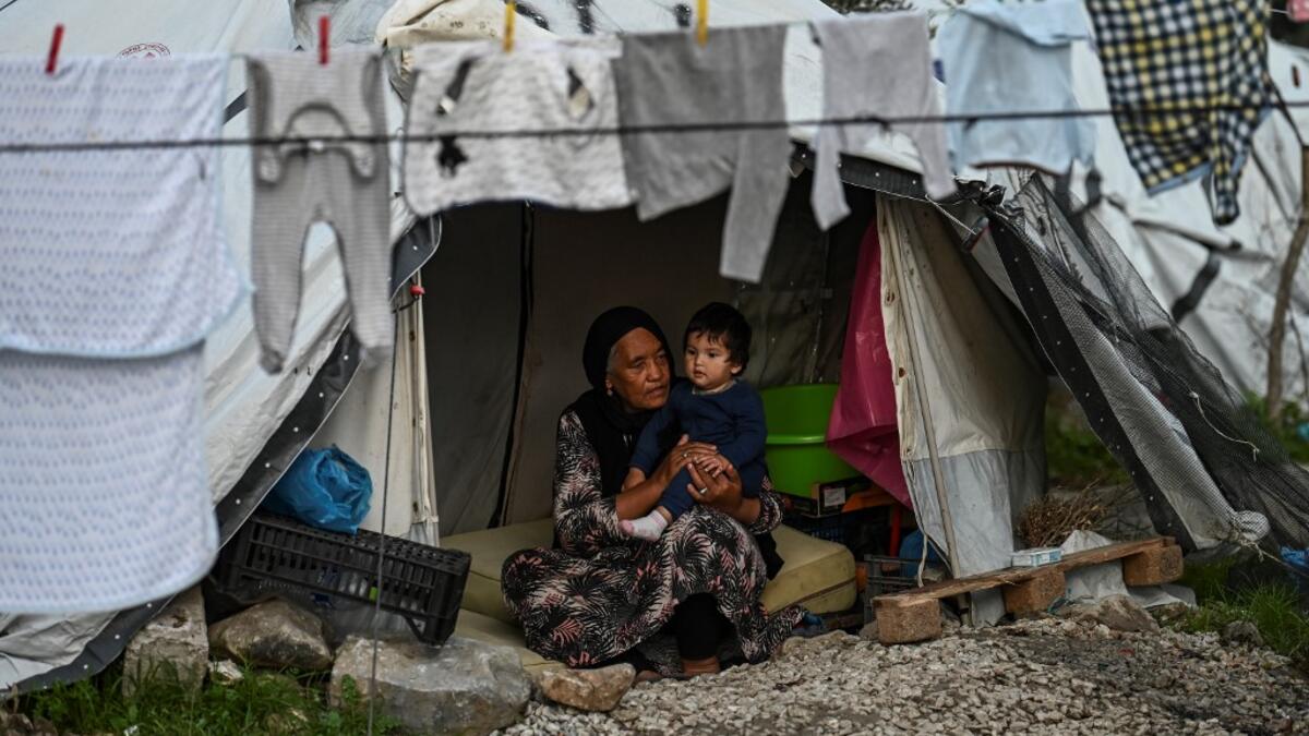 An eldery woman with her grandchild sit inside their tent at a makeshift camp next to the camp of Moria in the island of Lesbos on November 30, 2019. ARIS MESSINIS / AFP