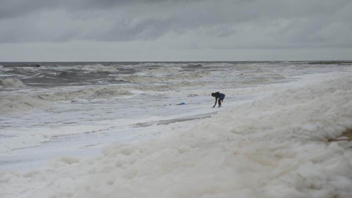 Residents play over foamy discharge, caused by pollutants, as it mixes with the surf at Marina beach in Chennai on December 1, 2019. Arun SANKAR / AFP
