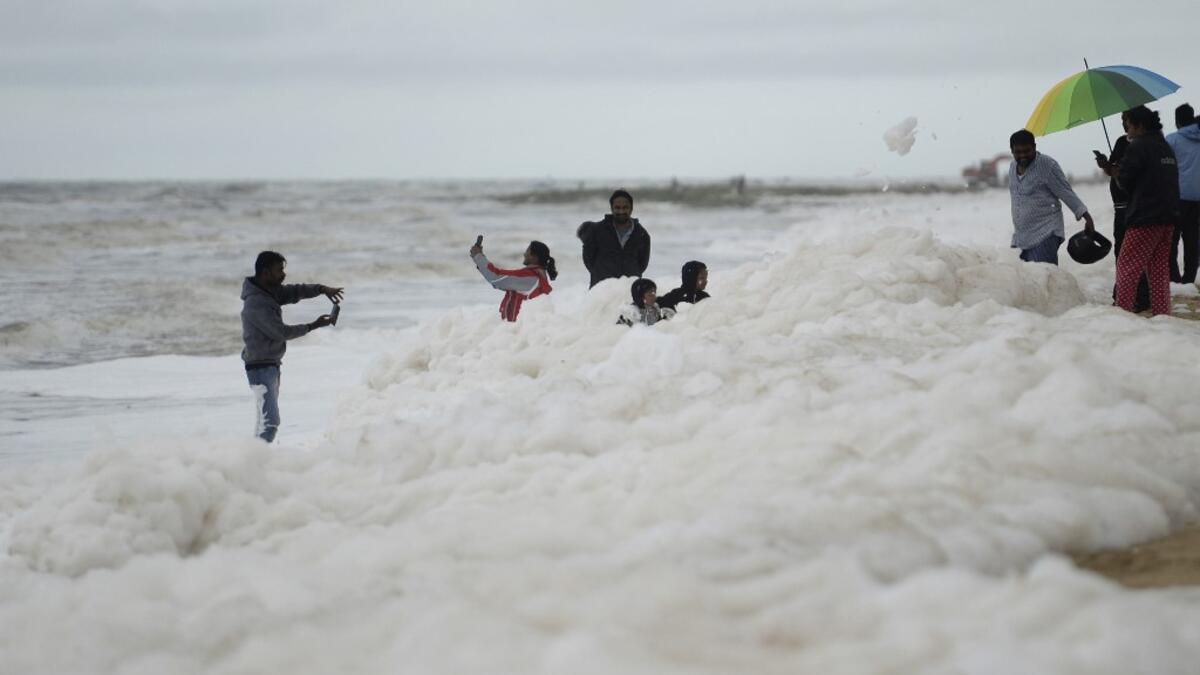 Residents take selfie pictures as foamy discharge, caused by pollutants, mix with surf at Marina beach in Chennai on December 1, 2019. Arun SANKAR / AFP