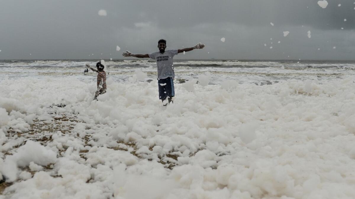 Residents play over foamy discharge, caused by pollutants, as it mixes with the surf at Marina beach in Chennai on December 1, 2019. Arun SANKAR / AFP