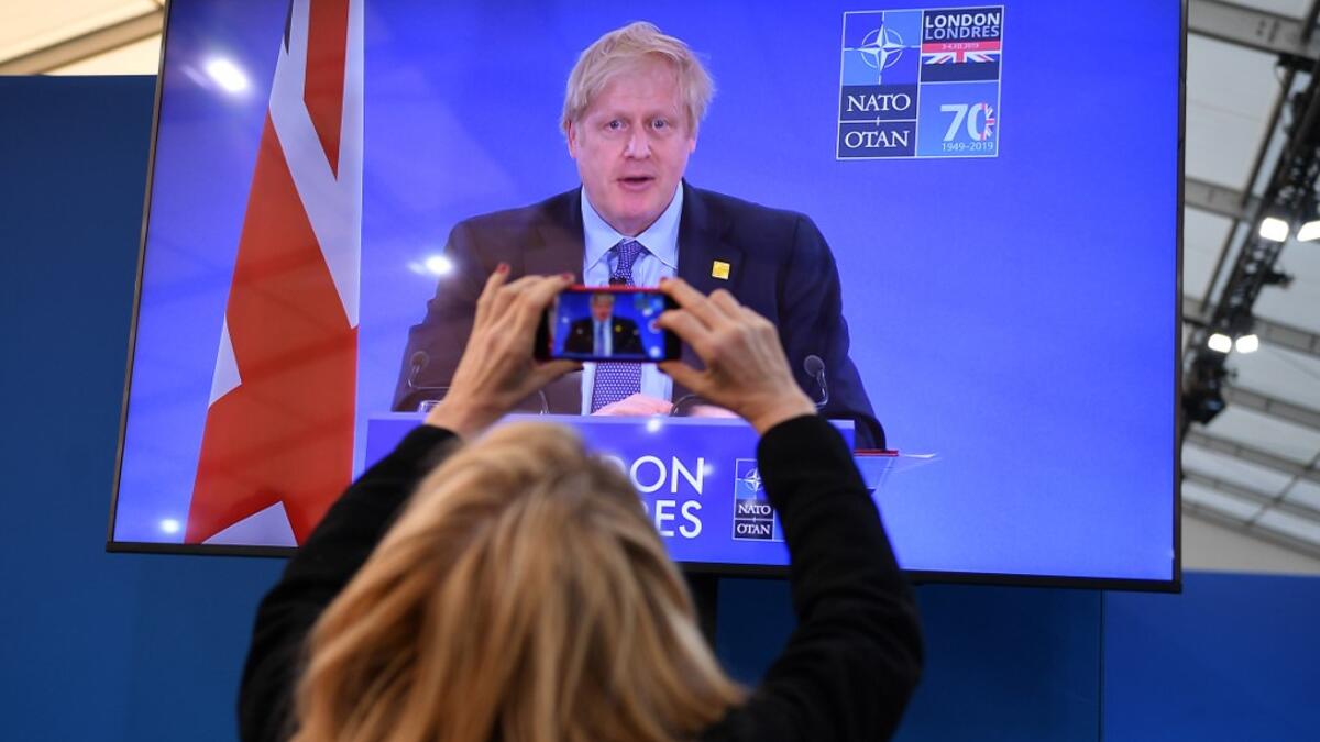 A journalist takes a picture of a television screen as Britain's Prime Minister Boris Johnson speaks during a press conference at the NATO summit at the Grove hotel in Watford, northeast of London on December 4, 2019. DANIEL LEAL-OLIVAS / AFP