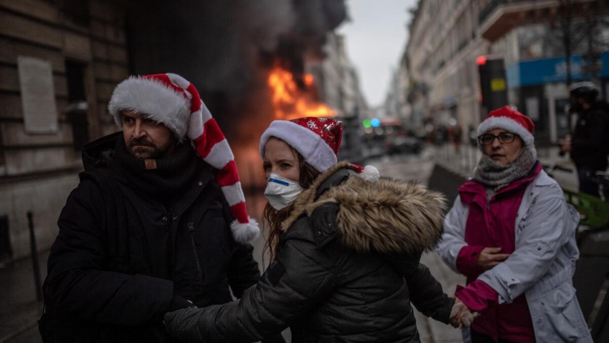 People wearing Christmas hats try to make their way in the streets of Paris during a demonstration over the pension overhauls, on December 5, 2019 as part of a national general strike. BULENT KILIC / AFP