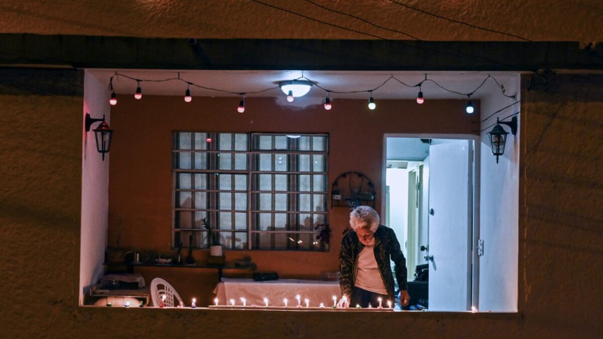 A woman lights a candle at the Comuna 13 in Medellin, Colombia, on December 7, 2019, on the Day of the Little Candles. The Day of the Little Candles is a traditional Colombian celebration which commemorates the Immaculate Conception of the Virgin Mary and marks the beginning of the Christmas season. On this day, light candles in their homes, on streets, and at cemeteries to decorate the graves of their dead. JOAQUIN SARMIENTO / AFP