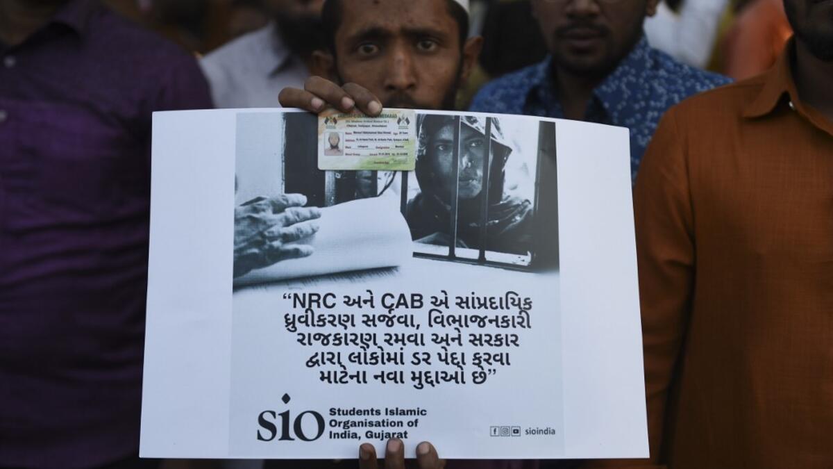 A Muslim man holds a placard as he participates along with others in a peaceful protest against the Citizenship Amendment Bill (CAB) and the National Register of Citizens (NRC) in Ahmedabad on December 15, 2019. Some 5,000 people took part in a fresh demonstration in Guwahati on December 15, with hundreds of police watching on as they sang, chanted and carried banners with the words "long live Assam". SAM PANTHAKY / AFP