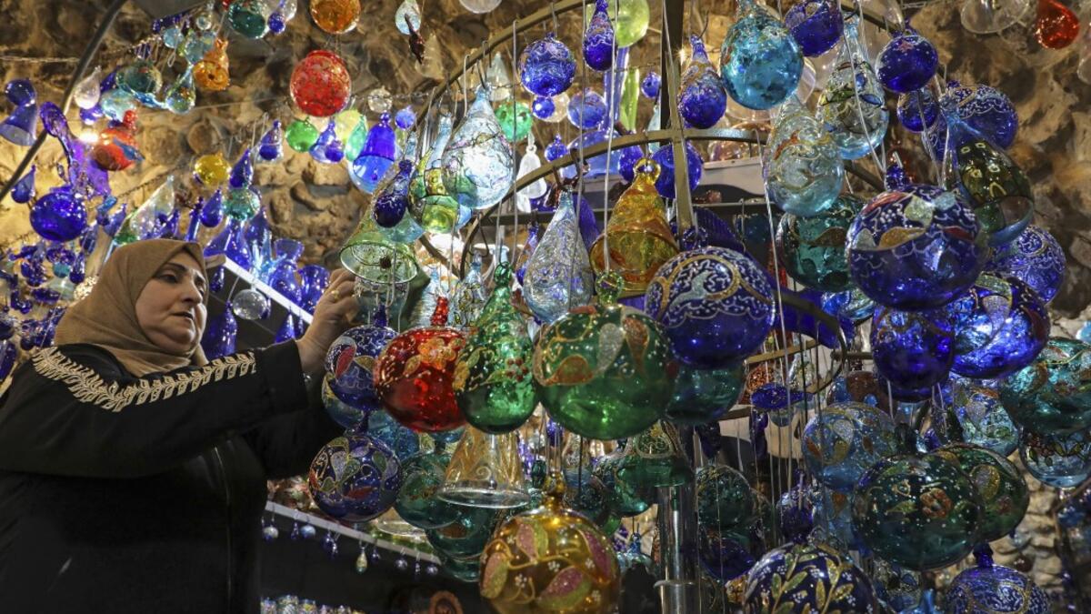 A Palestinian woman hangs glass Christmas ornaments on a display stand at a workshop in the southern West Bank city of Hebron, on December 15, 2019. HAZEM BADER / AFP