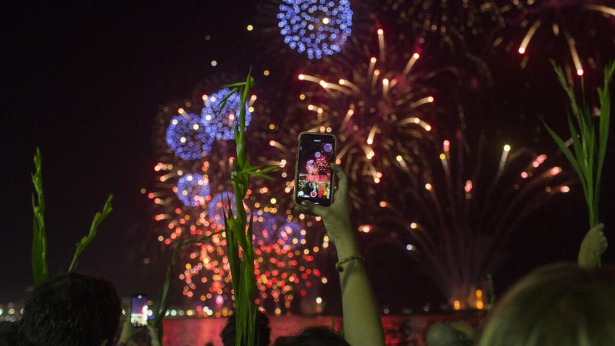 A woman takes pictures while celebrating with the traditional New Year's fireworks at Copacabana Beach in Rio de Janeiro, Brazil, on December 31, 2019. DANIEL RAMALHO / AFP