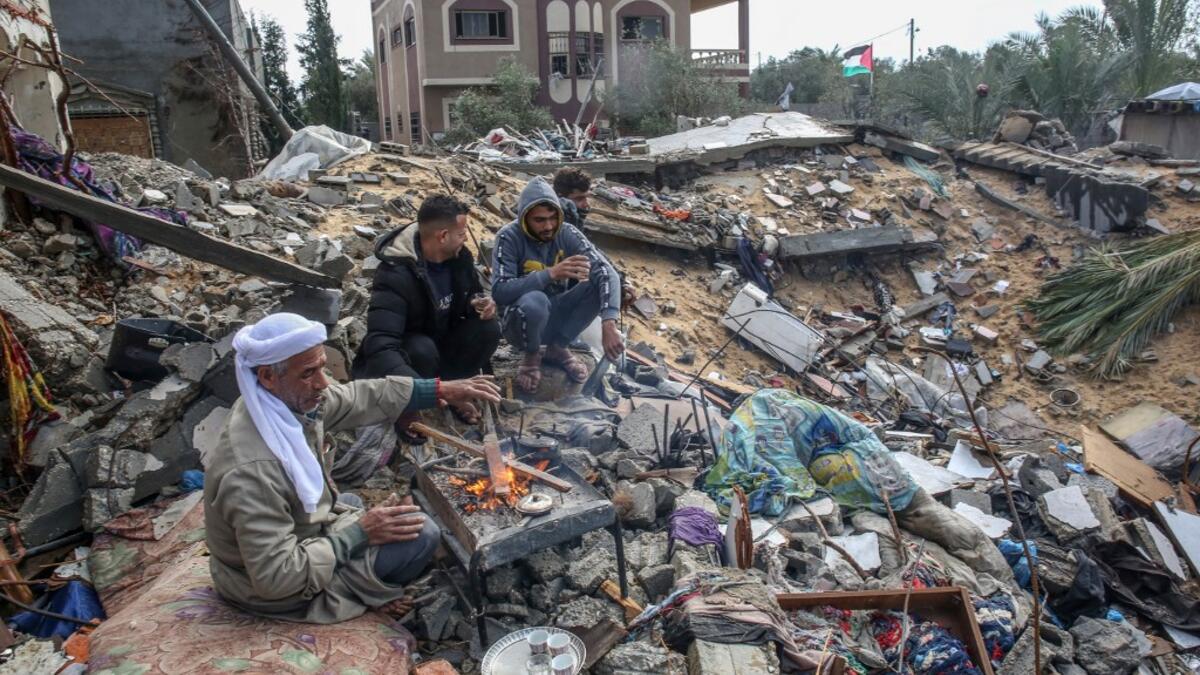 Palestinian Hammouda Abu Amra, 51, (L) sits with his sons on the site of his destroyed home in Khan Yunis in the southern Gaza Strip on January 10, 2020. Abu Amra, whose house was destroyed by an Israeli air strike last November, now lives in a shack with his family of seventeen. SAID KHATIB / AFP